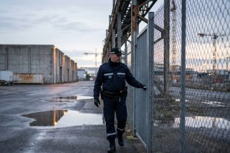 Agent rondier en uniforme effectuant une ronde périmétrique sur un site industriel à Nantes au crépuscule