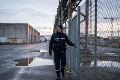 Agent rondier en uniforme effectuant une ronde périmétrique sur un site industriel à Nantes au crépuscule