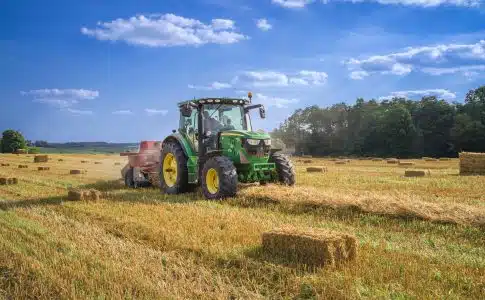 green tractor on brown grass field under blue sky during daytime