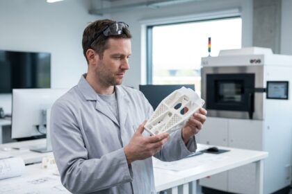Ingénieur examinant une pièce technique complexe imprimée en 3D par frittage sélectif laser SLS dans un atelier de conception industrielle moderne