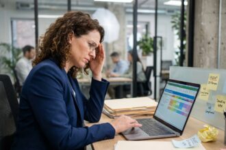 Responsable RH débordée gérant un planning de formation professionnelle sur ordinateur dans un open space